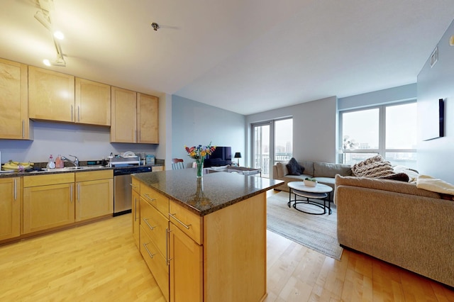 kitchen featuring dishwasher, light brown cabinets, light wood-style flooring, and open floor plan