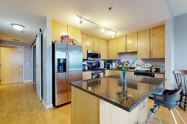 kitchen featuring stainless steel appliances, light brown cabinetry, a center island, a breakfast bar, and a barn door
