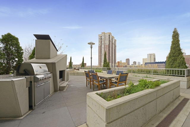 view of patio / terrace featuring an outdoor kitchen, outdoor dining area, a view of city, and fence