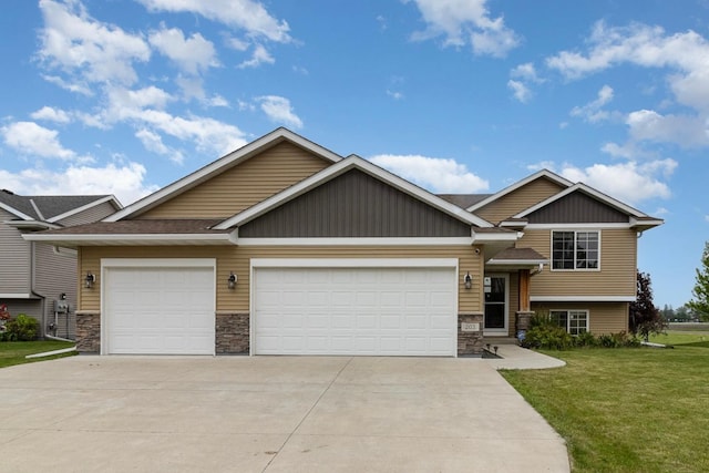 203 Kennedy Ave NW, New Prague, MN 56071 - view of front of home featuring stone siding, driveway, a front lawn, and a garage