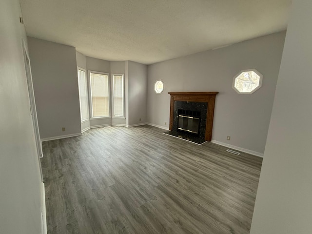 unfurnished living room featuring a fireplace, wood finished floors, visible vents, and baseboards