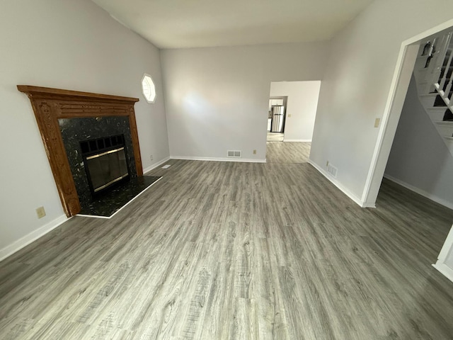 unfurnished living room featuring visible vents, baseboards, wood finished floors, and a fireplace