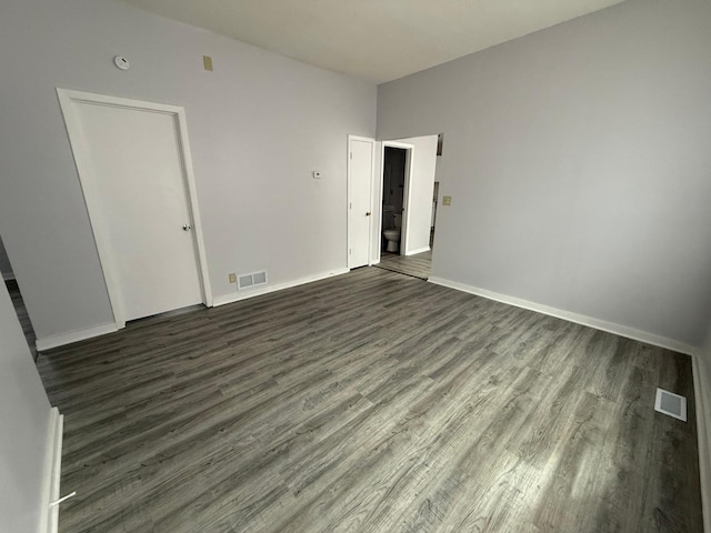 unfurnished room featuring baseboards, dark wood-type flooring, and visible vents