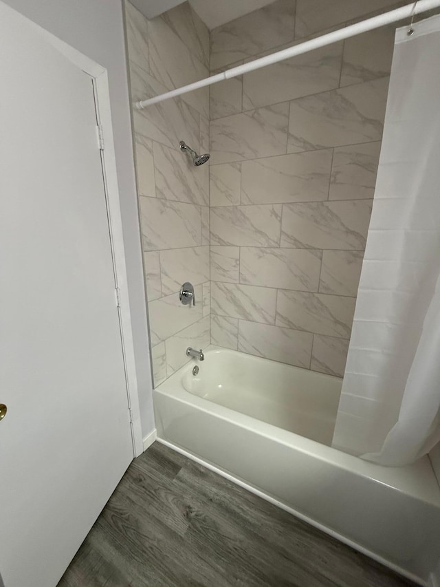 full bathroom featuring wood finished floors and shower / bathtub combination with curtain