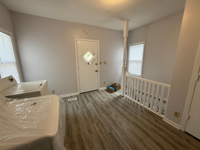 washroom featuring a textured ceiling, wood finished floors, washer / dryer, baseboards, and laundry area