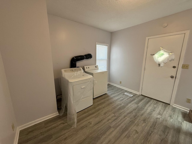 washroom featuring dark wood finished floors, laundry area, baseboards, separate washer and dryer, and a textured ceiling