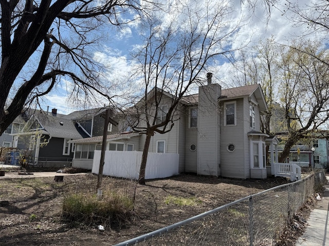 view of side of home featuring a chimney and fence private yard