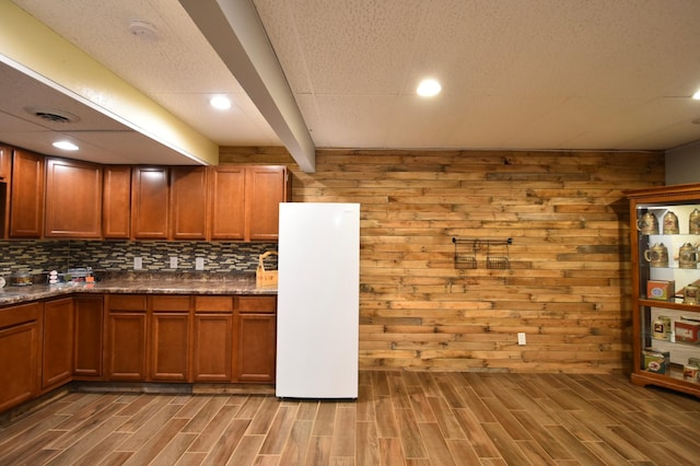 kitchen featuring wood finish floors, brown cabinets, freestanding refrigerator, and visible vents