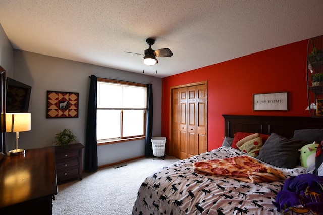 bedroom with a closet, carpet flooring, visible vents, a ceiling fan, and a textured ceiling