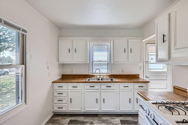 kitchen with white cabinets, wooden counters, and a sink