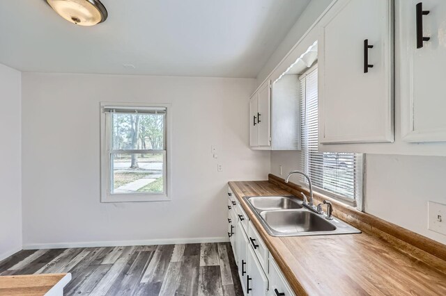 kitchen featuring a sink, butcher block countertops, white cabinetry, and dark wood-style flooring