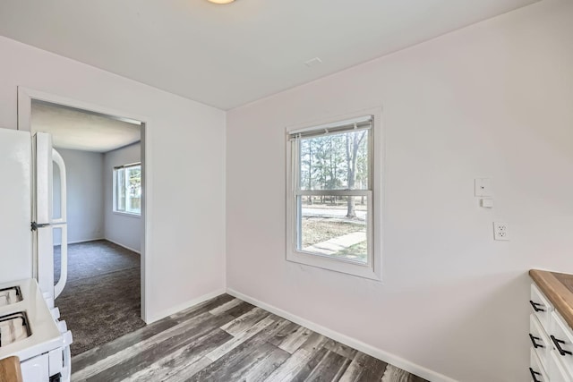 unfurnished dining area with wood finished floors and baseboards
