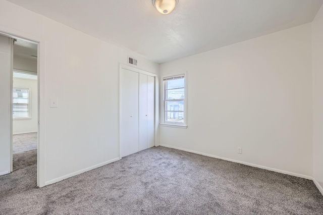 unfurnished bedroom with carpet, visible vents, baseboards, and multiple windows