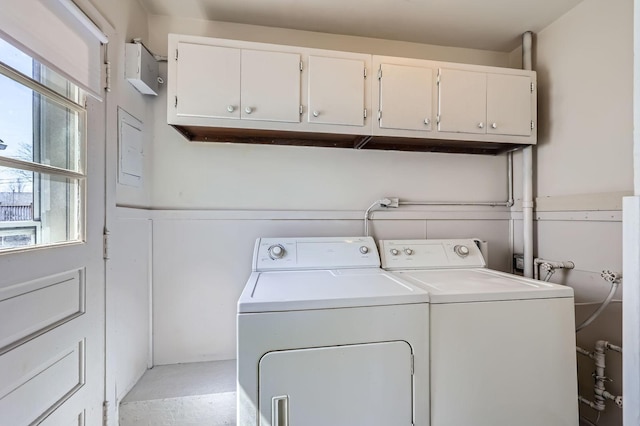 clothes washing area with separate washer and dryer, cabinet space, and a wainscoted wall