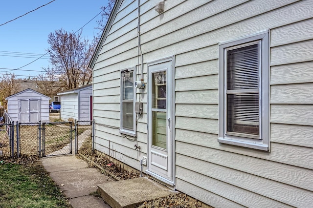 view of side of home featuring fence, an outdoor structure, a gate, and a shed