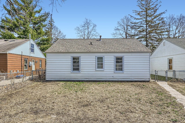rear view of house featuring a lawn, a shingled roof, and a fenced backyard