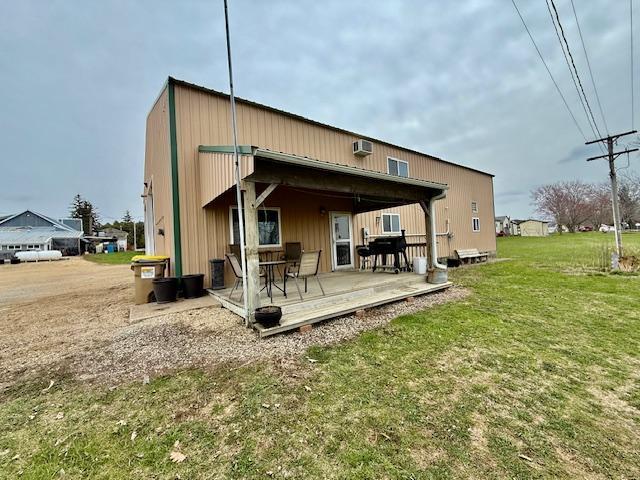 back of property with a deck, a yard, and a wall unit AC