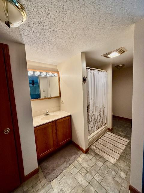 full bathroom featuring vanity, visible vents, baseboards, a textured ceiling, and a shower with shower curtain