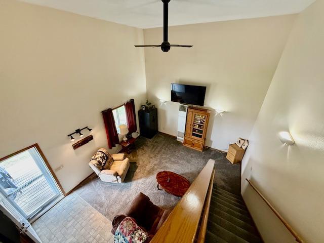 carpeted living area featuring a towering ceiling, ceiling fan, and plenty of natural light