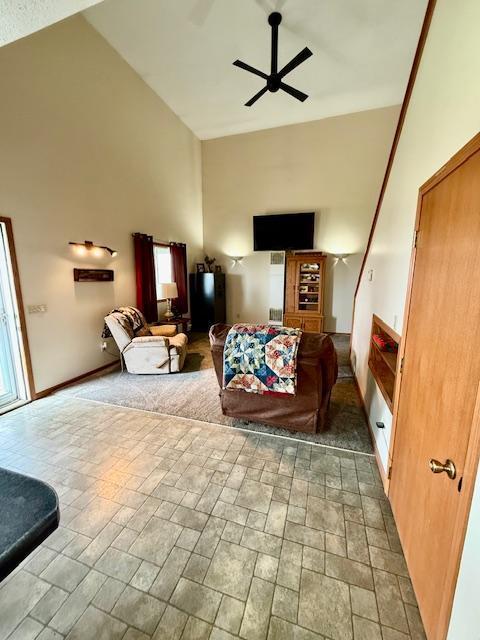 living area with ceiling fan, a wealth of natural light, and high vaulted ceiling