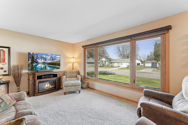 living room with a glass covered fireplace, carpet, and baseboards