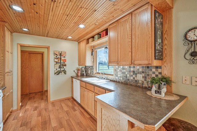 kitchen with a sink, white dishwasher, light wood-type flooring, decorative backsplash, and a peninsula