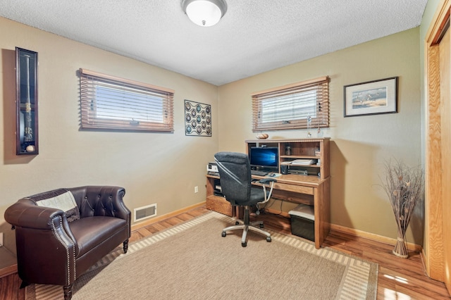 office space with a healthy amount of sunlight, wood finished floors, and visible vents