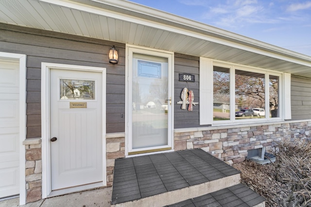 view of exterior entry with a porch and stone siding