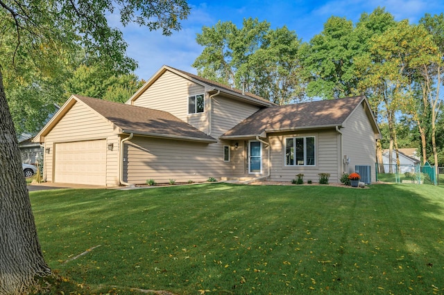 split level home featuring an attached garage, fence, a shingled roof, and a front yard