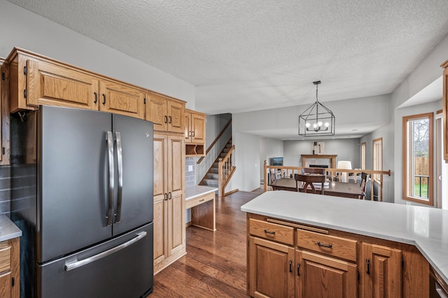 kitchen with freestanding refrigerator, pendant lighting, dark wood-style floors, light countertops, and a textured ceiling