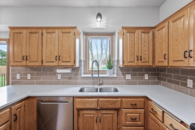 kitchen featuring plenty of natural light, a sink, dishwasher, and tasteful backsplash
