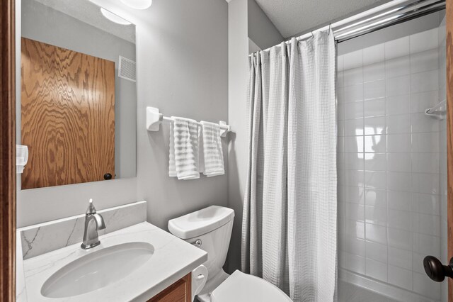 bathroom featuring toilet, a tile shower, and vanity