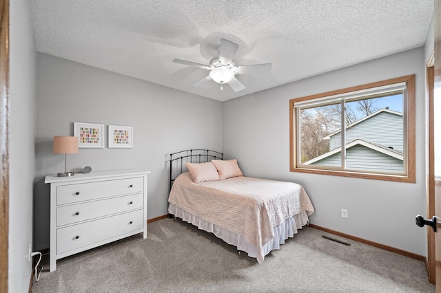 carpeted bedroom with baseboards, a ceiling fan, a textured ceiling, and visible vents