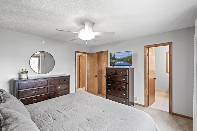 carpeted bedroom featuring baseboards, ceiling fan, visible vents, and ensuite bathroom