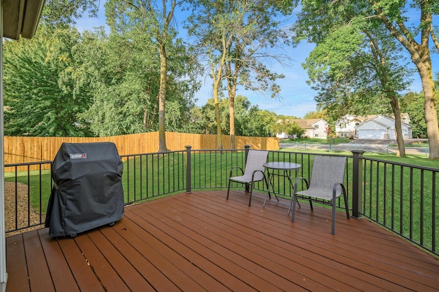 wooden terrace featuring fence, a yard, and a grill