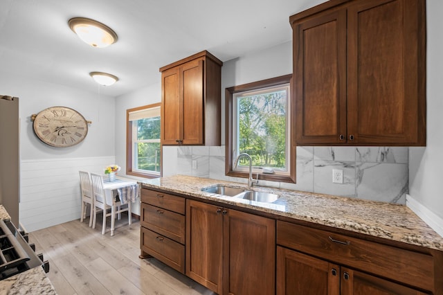 5840 Nevada Ave N, Crystal, MN 55428 - kitchen with a sink, light stone counters, wainscoting, light wood-style floors, and backsplash