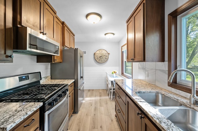5840 Nevada Ave N, Crystal, MN 55428 - kitchen featuring appliances with stainless steel finishes, plenty of natural light, a sink, wainscoting, and light wood-type flooring