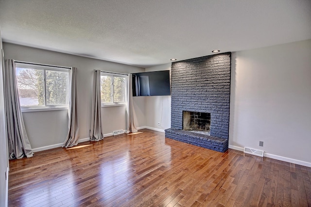 25755 E Comfort Dr, Wyoming, MN 55013 - unfurnished living room featuring a fireplace, visible vents, and hardwood / wood-style flooring