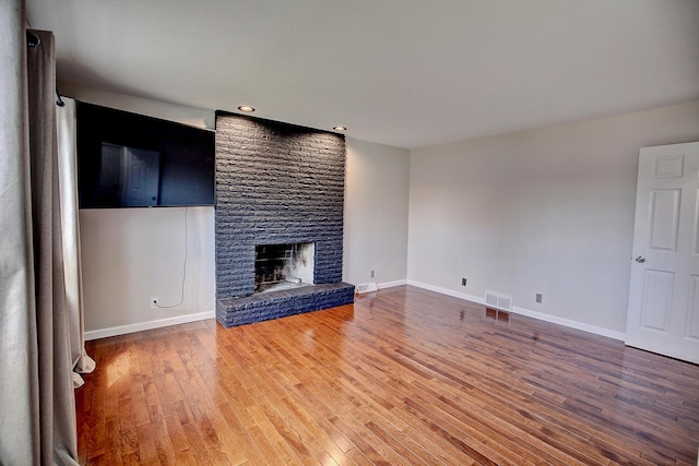 25755 E Comfort Dr, Wyoming, MN 55013 - unfurnished living room featuring baseboards, visible vents, recessed lighting, wood finished floors, and a brick fireplace