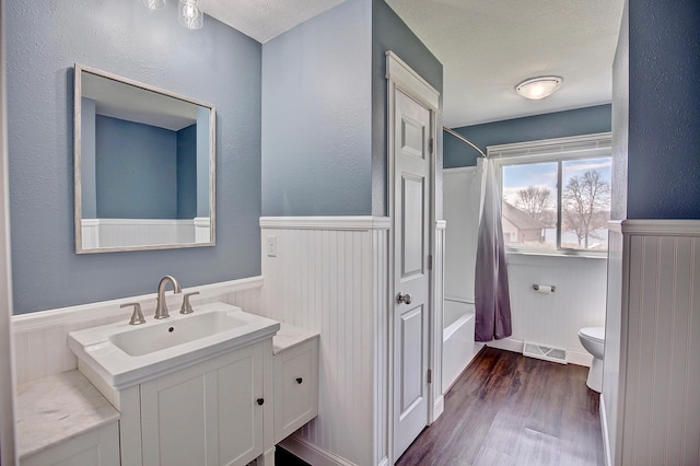 25755 E Comfort Dr, Wyoming, MN 55013 - full bathroom with wood finished floors, shower / tub combo with curtain, a wainscoted wall, toilet, and visible vents