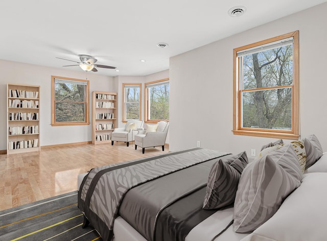 bedroom with visible vents, multiple windows, and wood finished floors