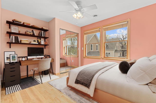 bedroom featuring visible vents, a closet, wood finished floors, baseboards, and a ceiling fan