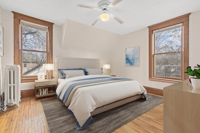 bedroom featuring baseboards, radiator, ceiling fan, and light wood-style floors