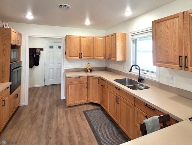 409 Prairieview St, St Thomas, ND 58276 - kitchen featuring light wood-style flooring, black oven, a sink, visible vents, and built in microwave