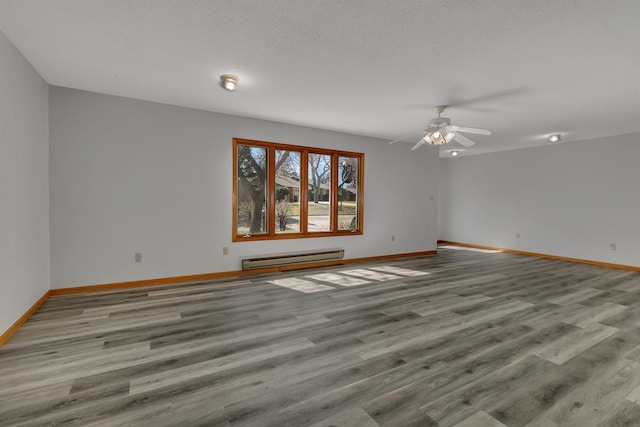 unfurnished room with baseboard heating, baseboards, and wood finished floors