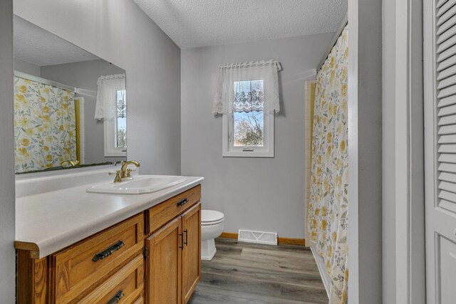 full bathroom with toilet, visible vents, baseboards, a textured ceiling, and wood finished floors