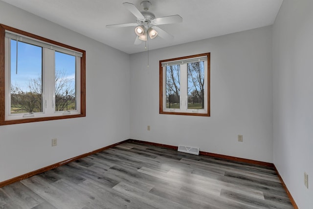 empty room featuring baseboards, visible vents, wood finished floors, and a ceiling fan