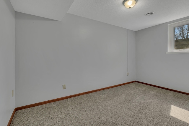 spare room with baseboards, visible vents, a textured ceiling, and carpet