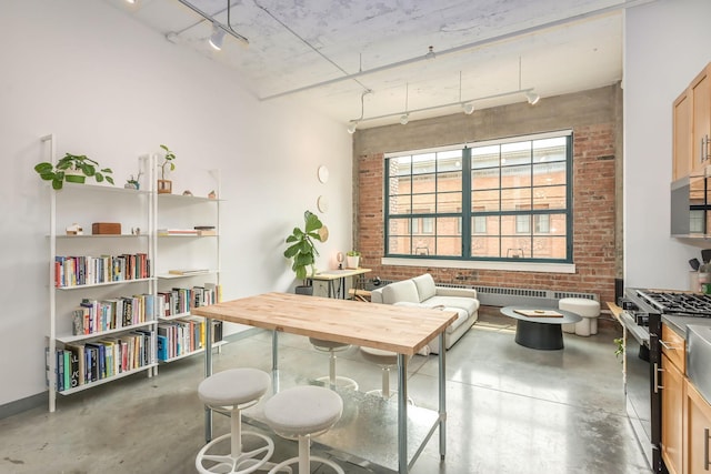 250 Park Ave Unit 601, Minneapolis, MN 55415 - kitchen with gas range oven, concrete floors, track lighting, brick wall, and radiator heating unit