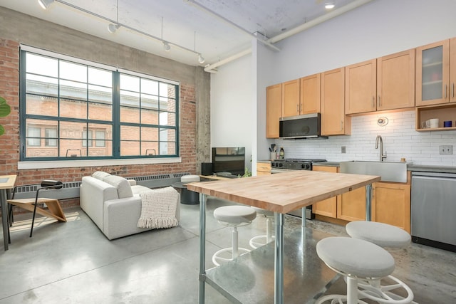 250 Park Ave Unit 601, Minneapolis, MN 55415 - kitchen with stainless steel appliances, wood counters, concrete floors, decorative backsplash, and brick wall